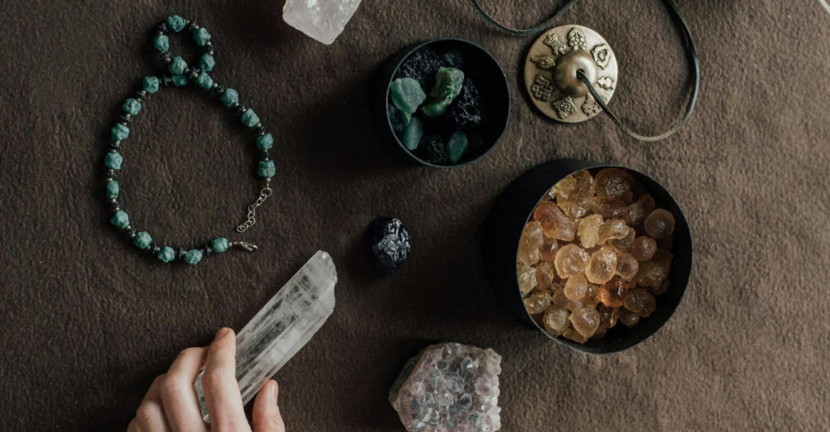Hand arranging spiritual tools and crystals on a natural brown cloth surface.